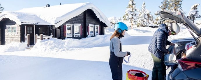 Barn och förälder som packar en bil i vintermiljö