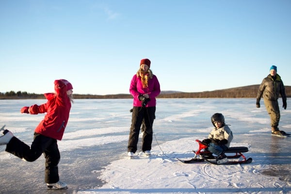 Familj som leker och åker skridskor på is